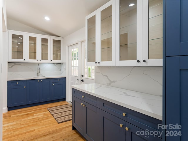 kitchen featuring lofted ceiling, white cabinetry, light hardwood / wood-style flooring, and tasteful backsplash