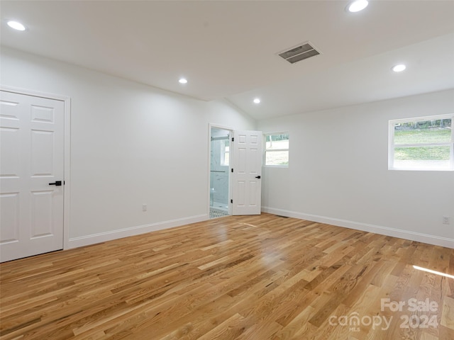 spare room featuring light wood-type flooring, lofted ceiling, and plenty of natural light