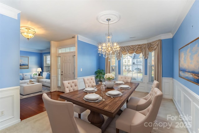 dining room featuring light wood-type flooring, an inviting chandelier, and crown molding