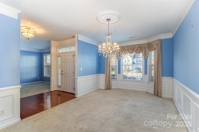 unfurnished dining area featuring ornamental molding, carpet flooring, and a chandelier