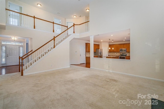 unfurnished living room featuring a high ceiling and light carpet