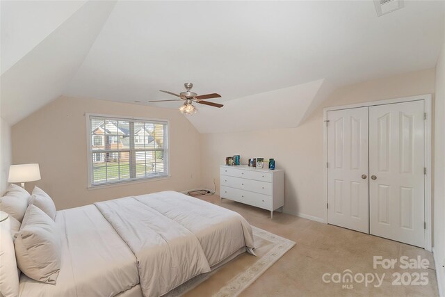 bedroom with lofted ceiling, light carpet, ceiling fan, and a closet