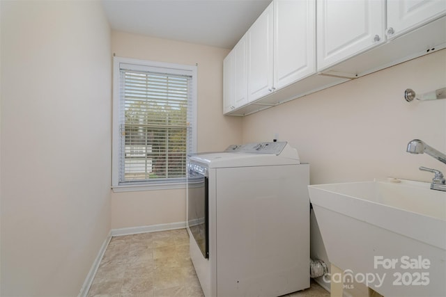 clothes washing area featuring sink, washer and clothes dryer, and cabinets