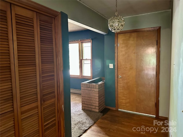 interior space featuring a baseboard radiator, hardwood / wood-style floors, and an inviting chandelier