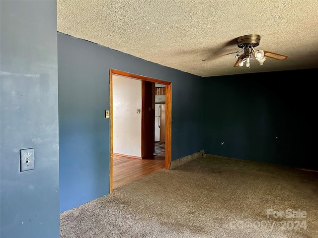 unfurnished room with a textured ceiling, carpet flooring, and ceiling fan