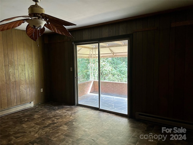 empty room featuring wood walls, a baseboard radiator, and ceiling fan