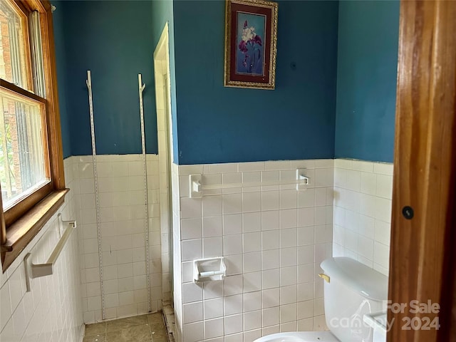 bathroom with toilet and tile walls