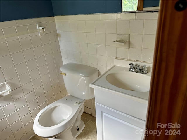 bathroom featuring toilet, vanity, tile patterned floors, and tile walls