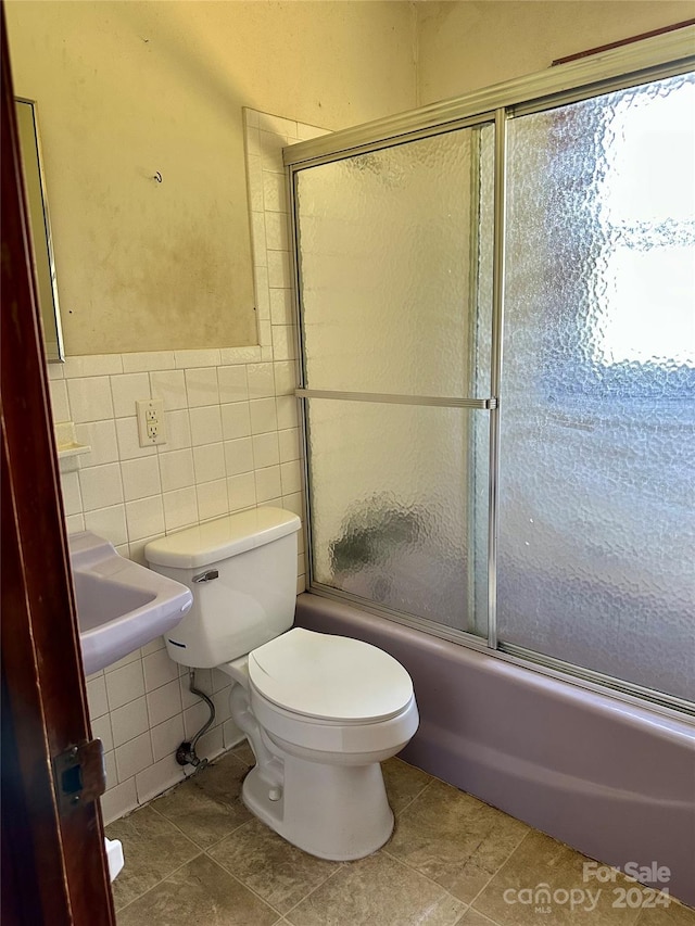 full bathroom with tile patterned floors, toilet, sink, tile walls, and shower / bath combination with glass door