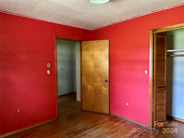 unfurnished bedroom featuring a closet, hardwood / wood-style flooring, and a textured ceiling