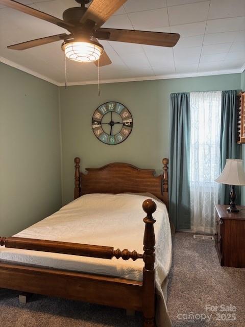 carpeted bedroom featuring ornamental molding and a ceiling fan