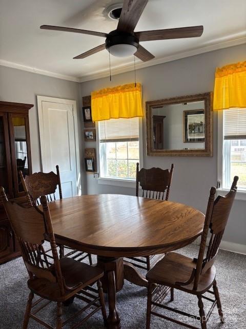 carpeted dining space with ornamental molding, baseboards, and a ceiling fan