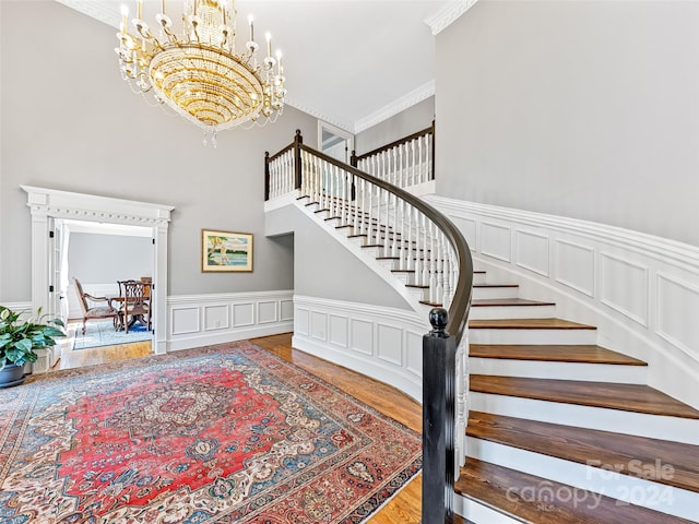 stairway with crown molding, hardwood / wood-style floors, and a notable chandelier