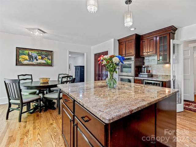 kitchen with beverage cooler, decorative light fixtures, a chandelier, light hardwood / wood-style floors, and decorative backsplash