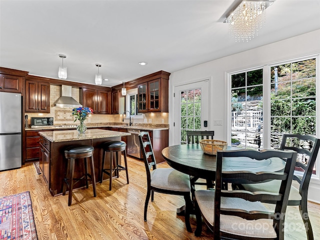 dining room featuring sink, light hardwood / wood-style flooring, and a notable chandelier