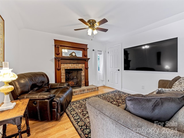 living room featuring ceiling fan, hardwood / wood-style flooring, and a fireplace