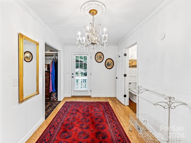 foyer entrance featuring light hardwood / wood-style flooring, crown molding, and a chandelier