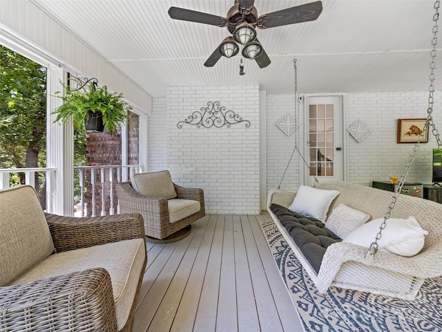 interior space featuring hardwood / wood-style flooring, ceiling fan, and brick wall