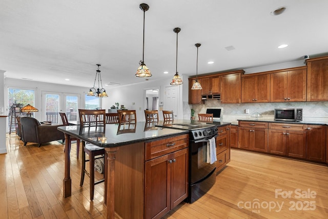 kitchen featuring black / electric stove, a breakfast bar, a kitchen island, and hanging light fixtures