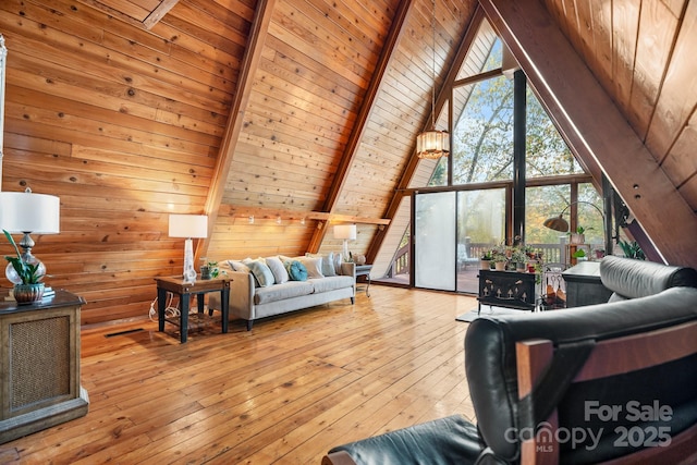 living room with vaulted ceiling with beams, wooden walls, wooden ceiling, and light wood-type flooring