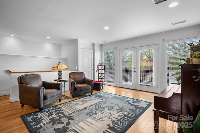 living area with french doors, crown molding, and light hardwood / wood-style flooring