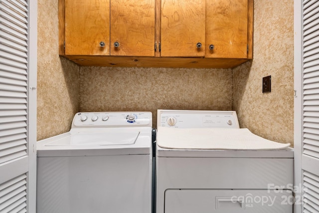 clothes washing area with cabinets and separate washer and dryer