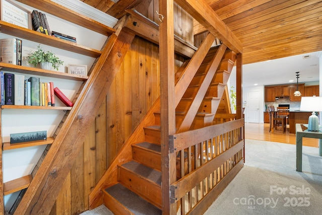 staircase featuring carpet floors and wood ceiling