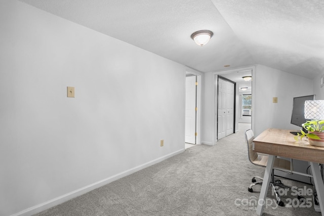 carpeted office with a textured ceiling and vaulted ceiling