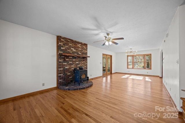 unfurnished living room featuring light wood-type flooring, a notable chandelier, and a wood stove