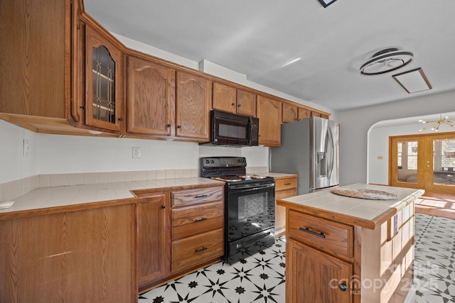 kitchen featuring black appliances, tile counters, and a kitchen island