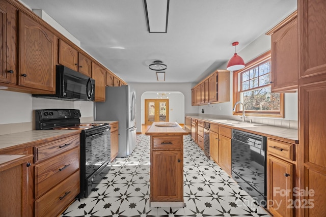 kitchen featuring tile countertops, sink, a center island, and black appliances