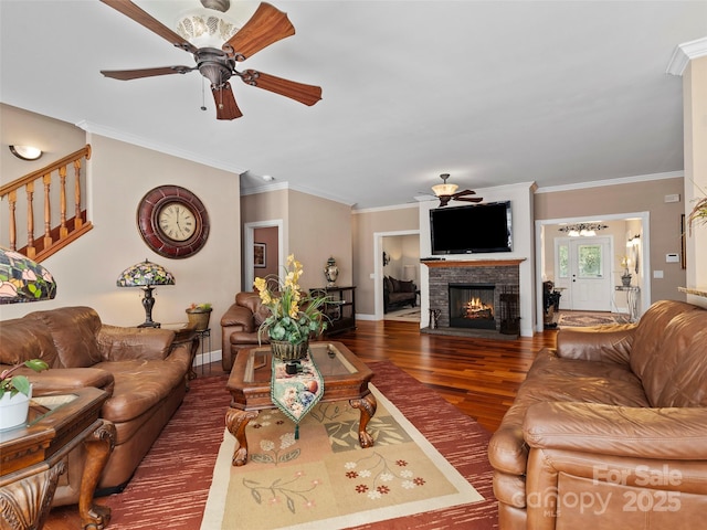 living room featuring a stone fireplace, crown molding, ceiling fan, and dark hardwood / wood-style floors