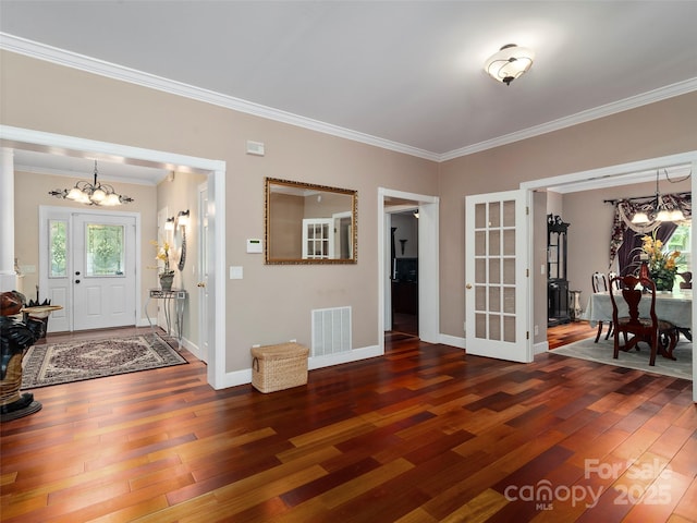 foyer entrance with ornamental molding, an inviting chandelier, and dark wood-type flooring