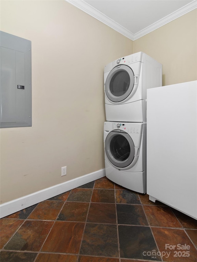 laundry area with stacked washer / drying machine, ornamental molding, and electric panel