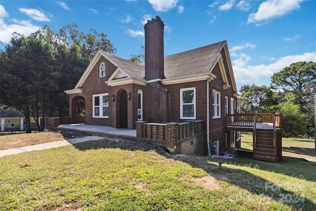 tudor home with a front yard and a deck