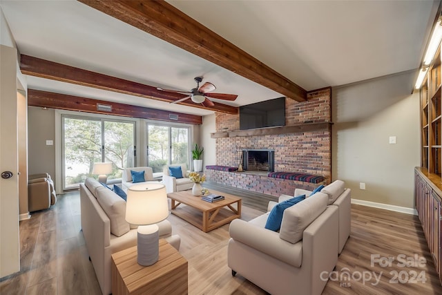 living room featuring light hardwood / wood-style floors, beamed ceiling, a fireplace, and ceiling fan