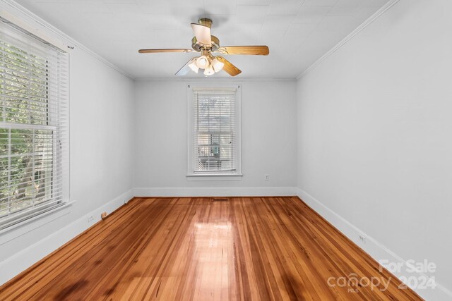 empty room with ornamental molding, hardwood / wood-style floors, and ceiling fan