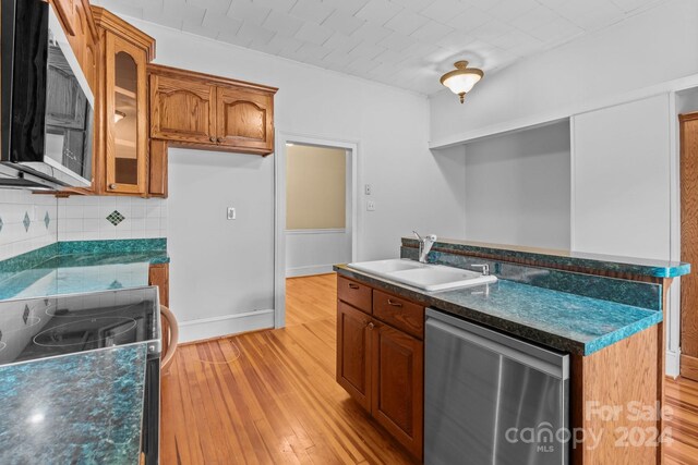 kitchen with backsplash, stove, light hardwood / wood-style flooring, stainless steel dishwasher, and sink