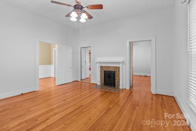 unfurnished living room with a tile fireplace, ceiling fan, and light hardwood / wood-style flooring