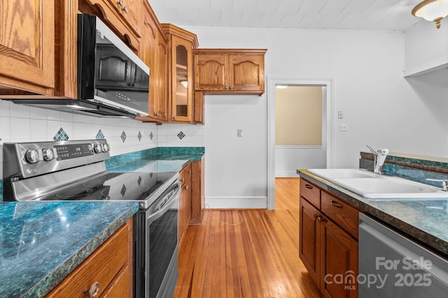 405 7th St, Spencer, NC 28159 - kitchen with stainless steel appliances, brown cabinets, dark countertops, light wood-type flooring, and backsplash