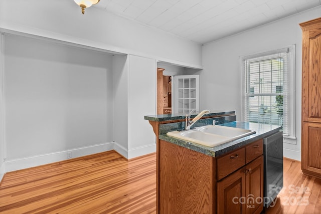 405 7th St, Spencer, NC 28159 - kitchen with light wood finished floors, a kitchen island with sink, dishwasher, brown cabinetry, and ornamental molding