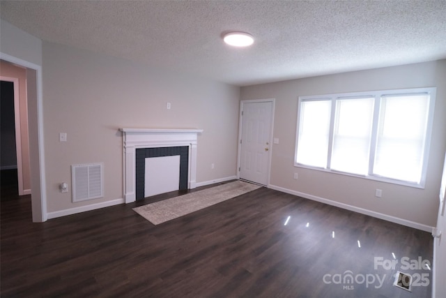 unfurnished living room with a textured ceiling, a fireplace, and dark wood-type flooring