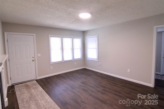 foyer entrance with a textured ceiling and dark hardwood / wood-style flooring