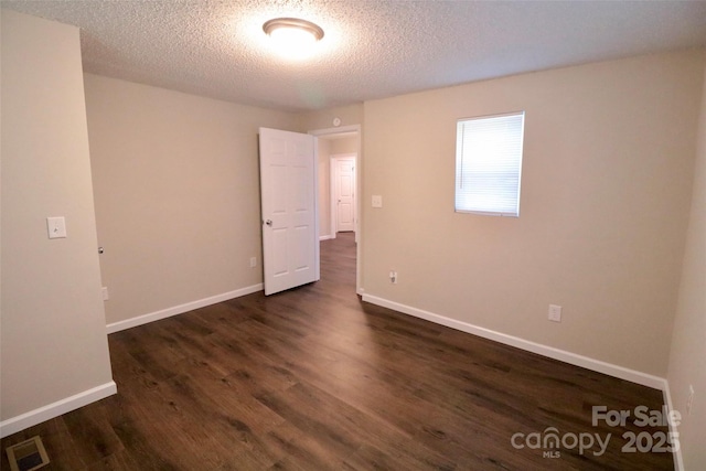 spare room with a textured ceiling and dark wood-type flooring