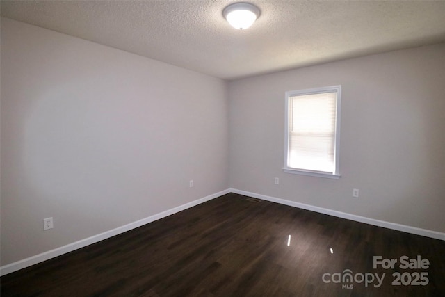 spare room featuring a textured ceiling and dark wood-type flooring