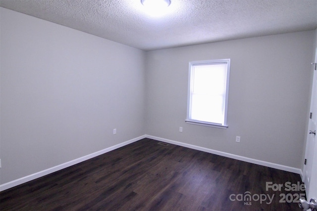 unfurnished room featuring a textured ceiling and dark wood-type flooring