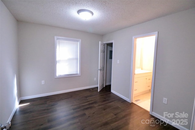 unfurnished bedroom featuring a textured ceiling, dark hardwood / wood-style floors, and connected bathroom