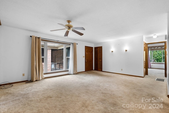 carpeted spare room with a textured ceiling and ceiling fan