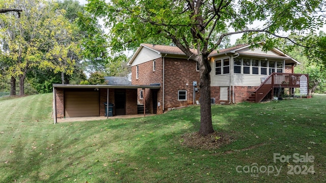 rear view of property featuring a yard, a sunroom, and a wooden deck