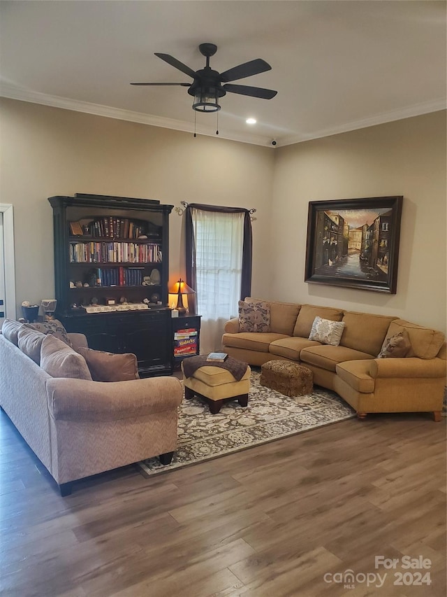 living room with crown molding, dark wood-type flooring, and ceiling fan